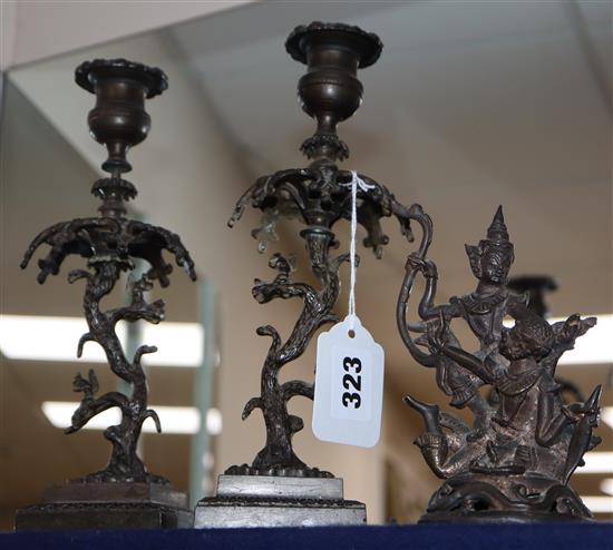 A pair of decorative metal candlesticks and a Thai deity